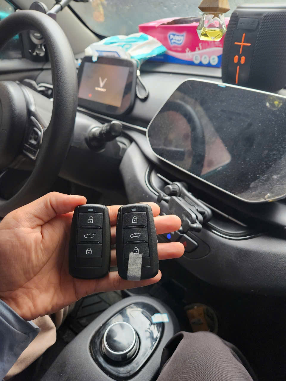 Hai chìa khóa ô tô thông minh màu đen được cầm trên tay trong khoang lái xe VinFast