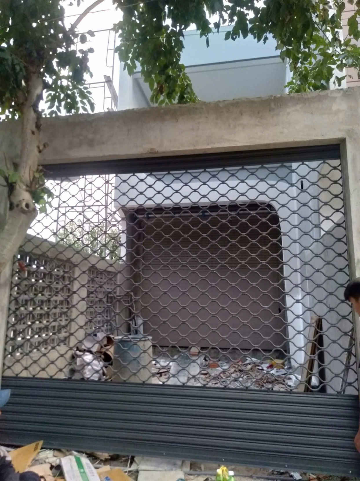 Cửa cuốn lưới mắt võng đang lắp đặt cho mặt tiền nhà phố đang xây dựng