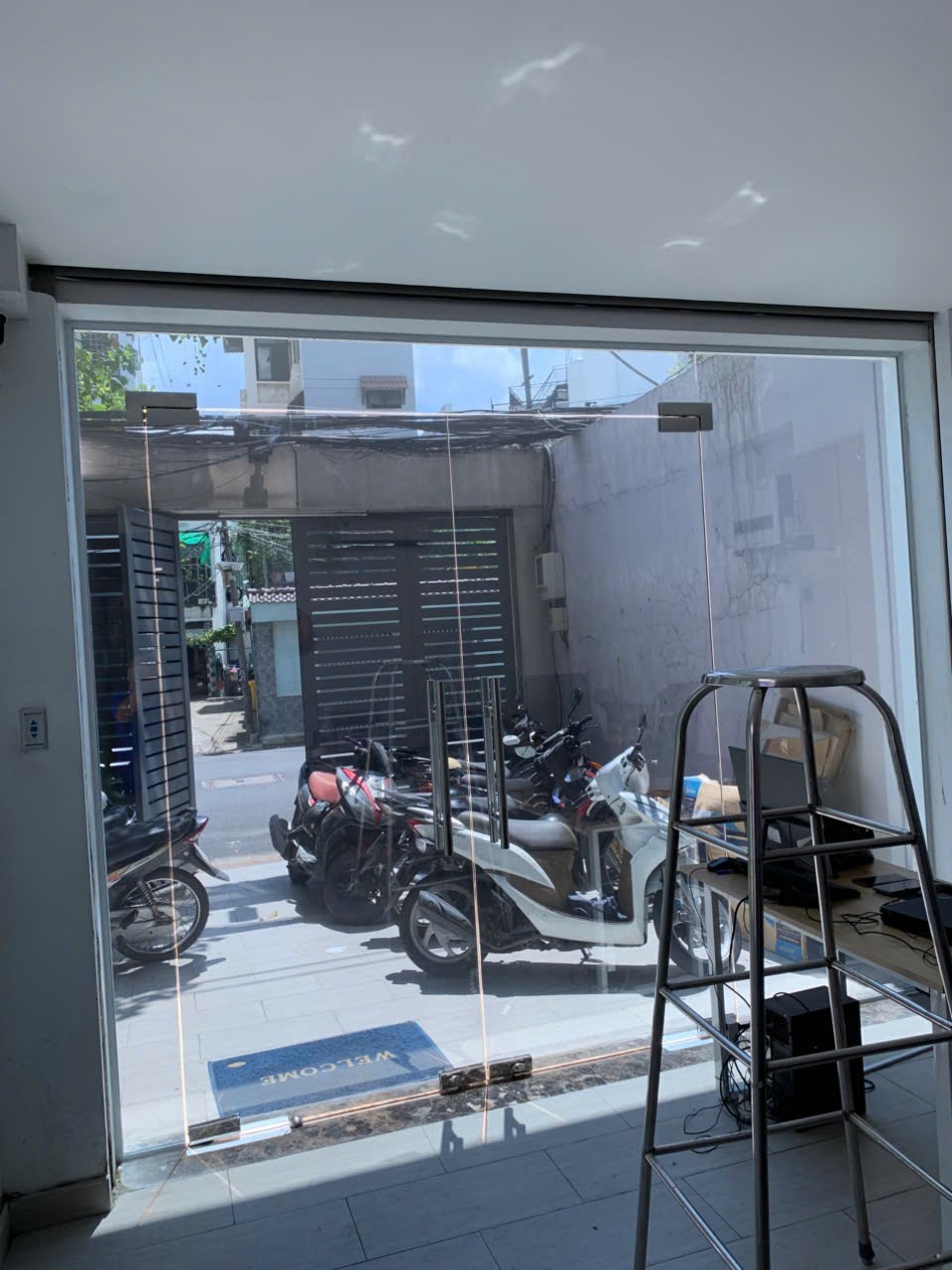 Cửa kính cường lực mặt tiền văn phòng với tay nắm inox nhìn ra bãi xe máy