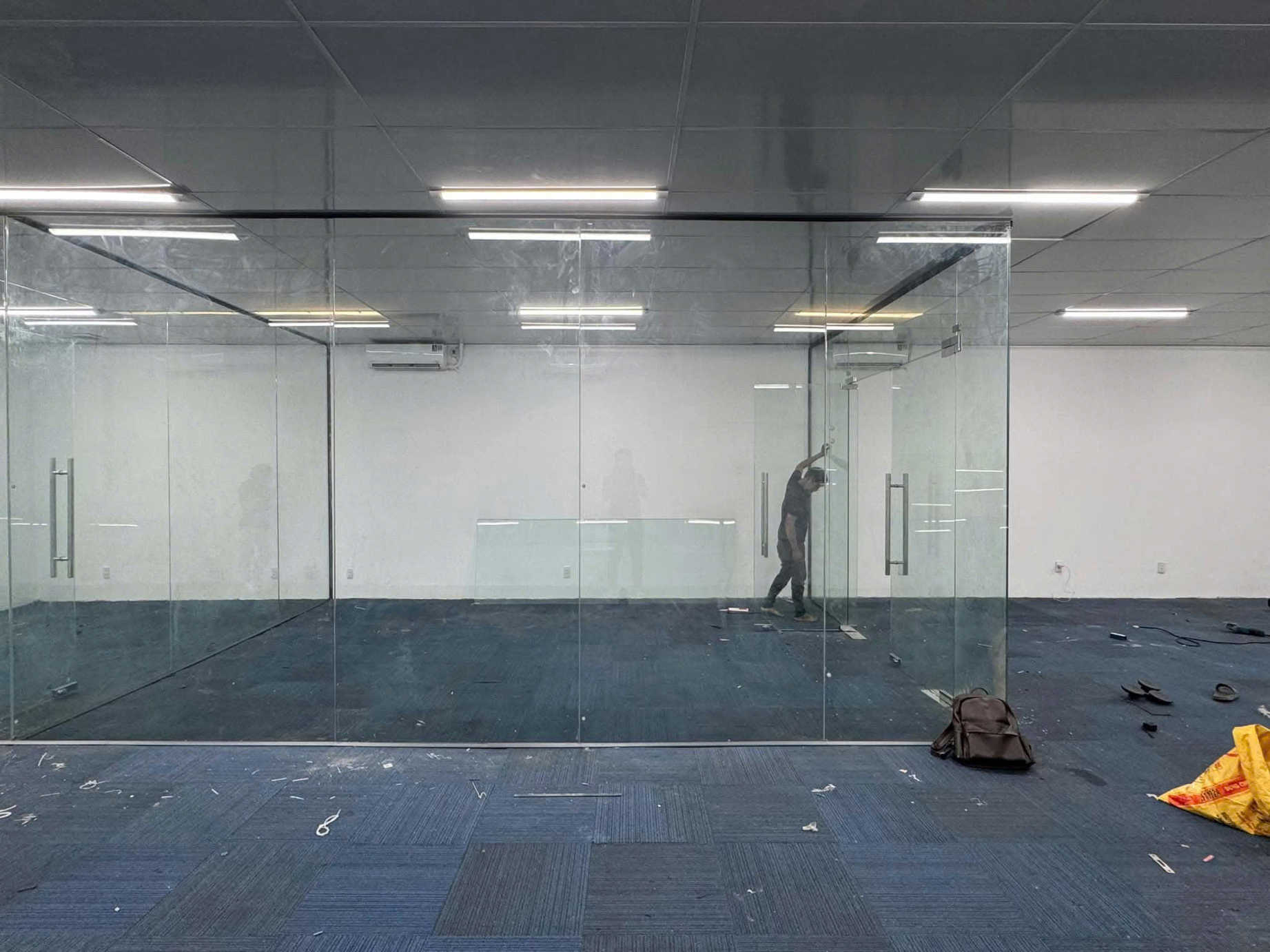 Vách kính cường lực văn phòng đang thi công với cửa kính khung nhôm và tay nắm inox