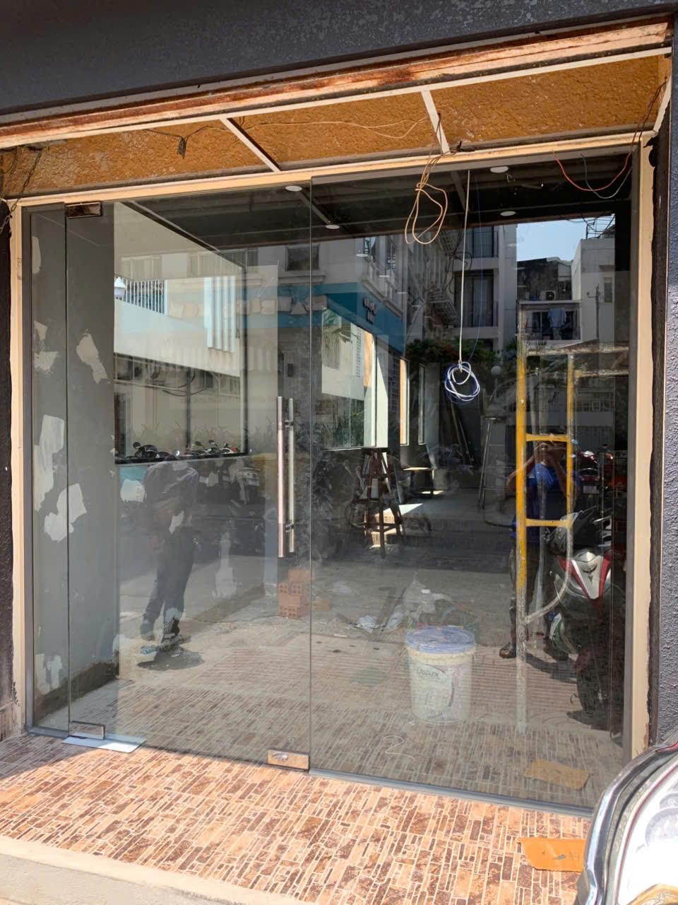 Cửa kính cường lực hai cánh khung nhôm cho mặt tiền cửa hàng đang thi công