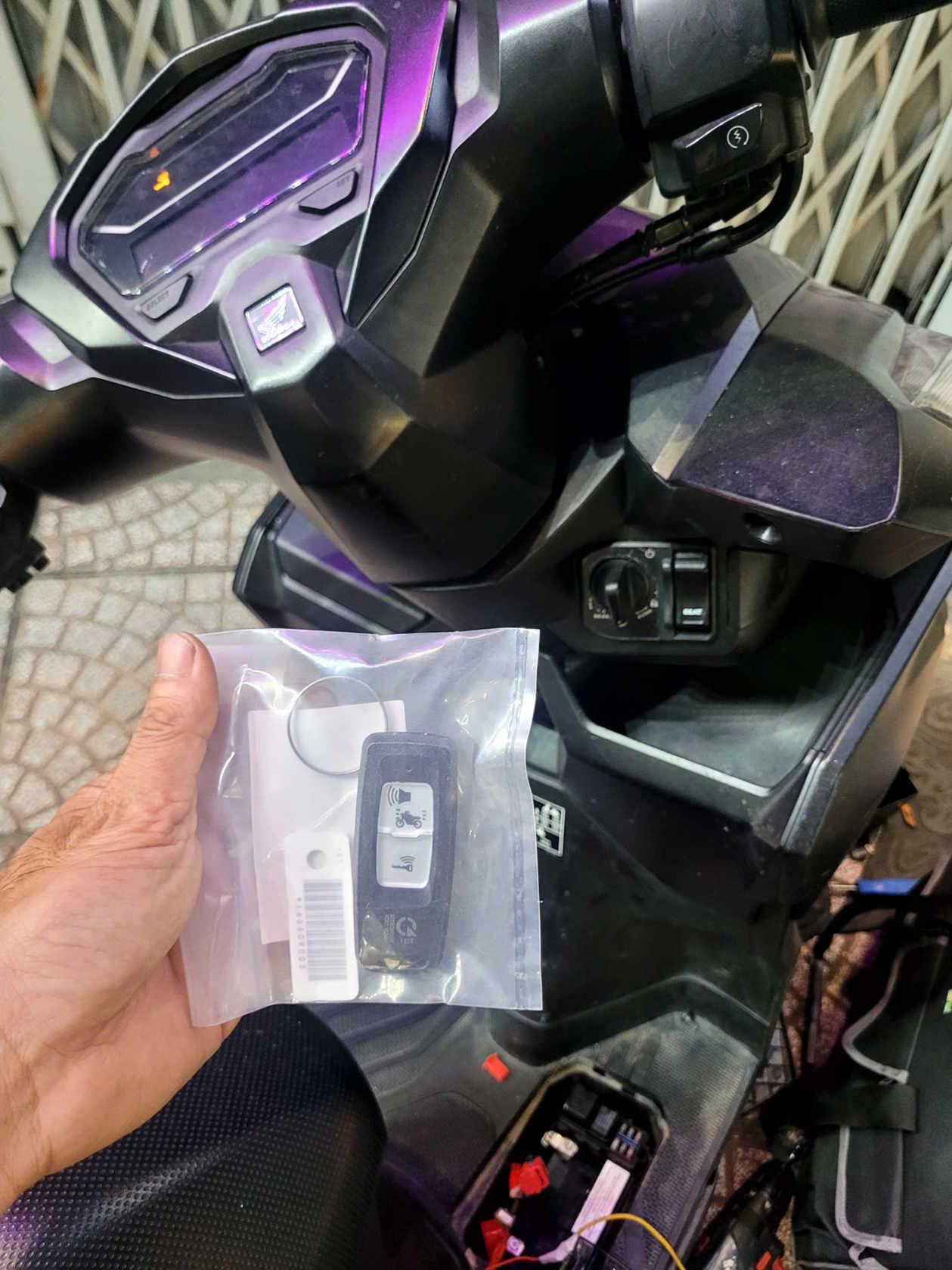 Chìa khóa thông minh xe máy Honda trong túi nhựa được cầm trước bảng điều khiển xe