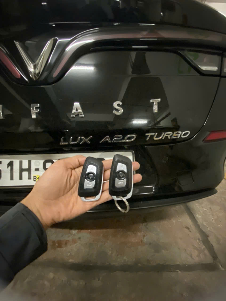 Chìa khóa ô tô VinFast Lux A2.0 Turbo màu đen cầm trước đuôi xe trong hầm gửi xe