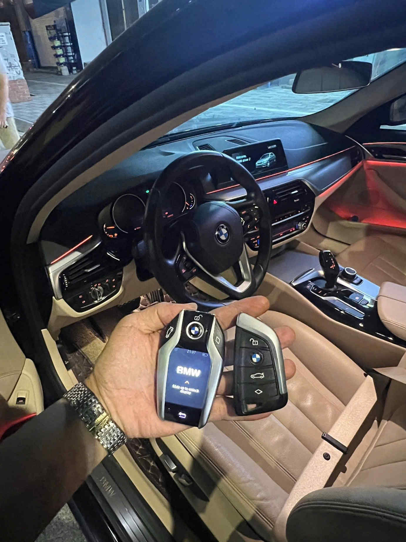 Chìa khóa thông minh BMW trên tay người dùng trước nội thất xe BMW cao cấp bật đèn nội thất