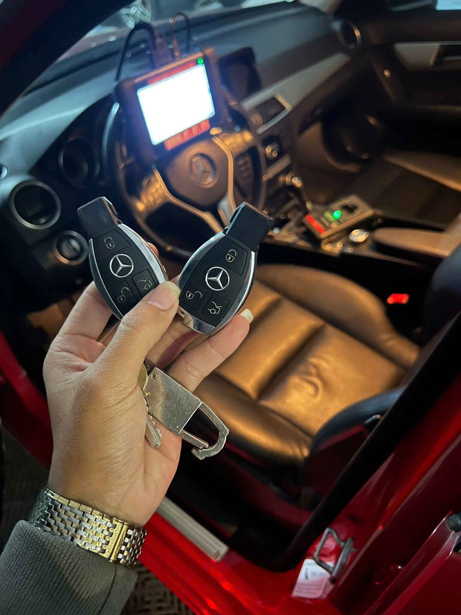 Chìa khóa thông minh Mercedes Benz cầm trên tay trước nội thất xe Mercedes màu đen