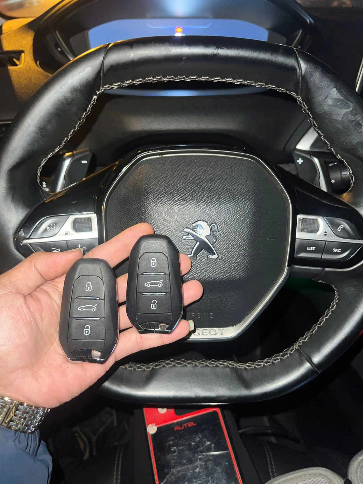 Chìa khóa thông minh ô tô Peugeot trên tay tài xế trước vô lăng xe Peugeot