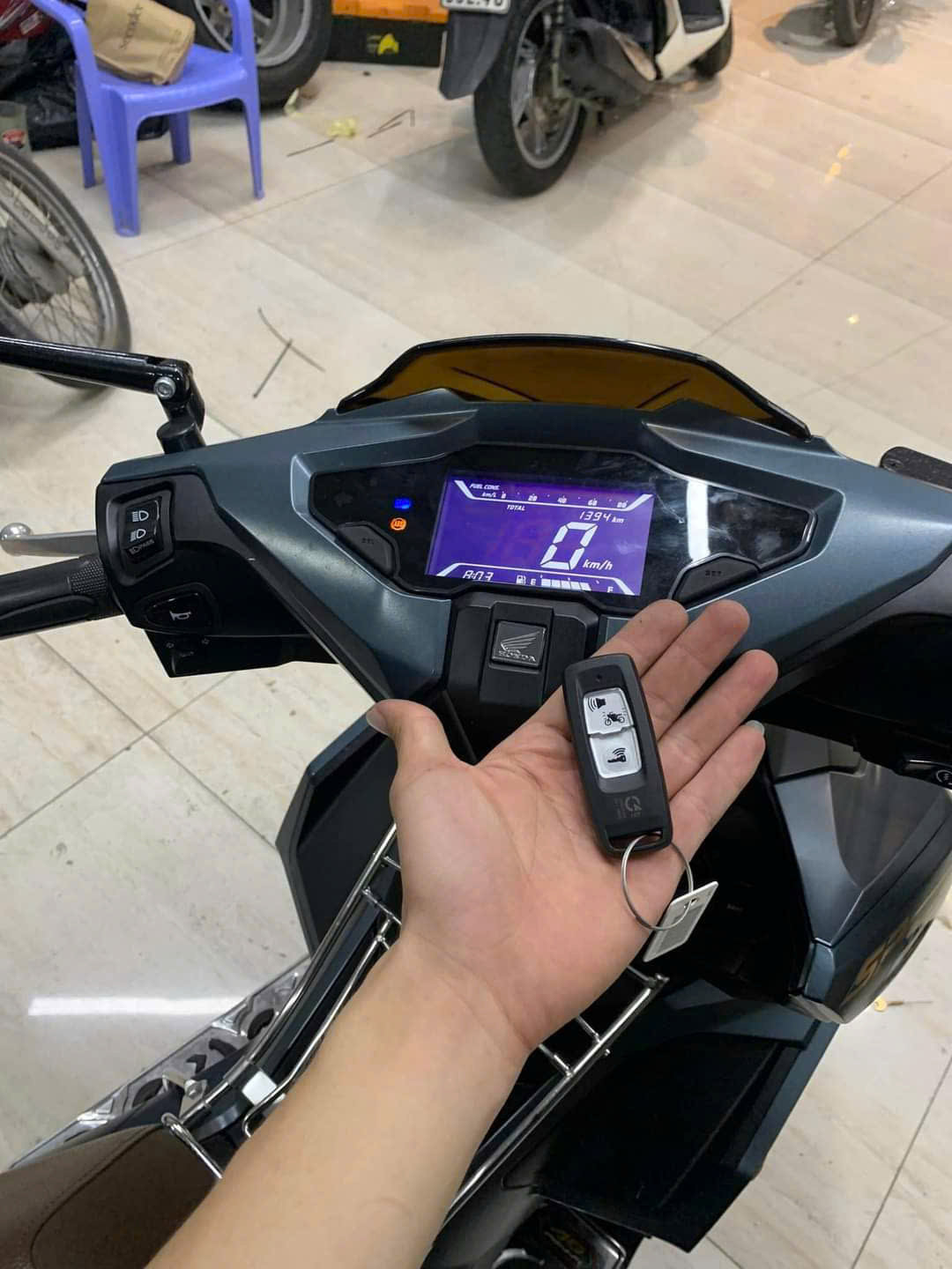 Tay cầm chìa khóa thông minh xe máy Honda trước bảng đồng hồ điện tử trên tay lái