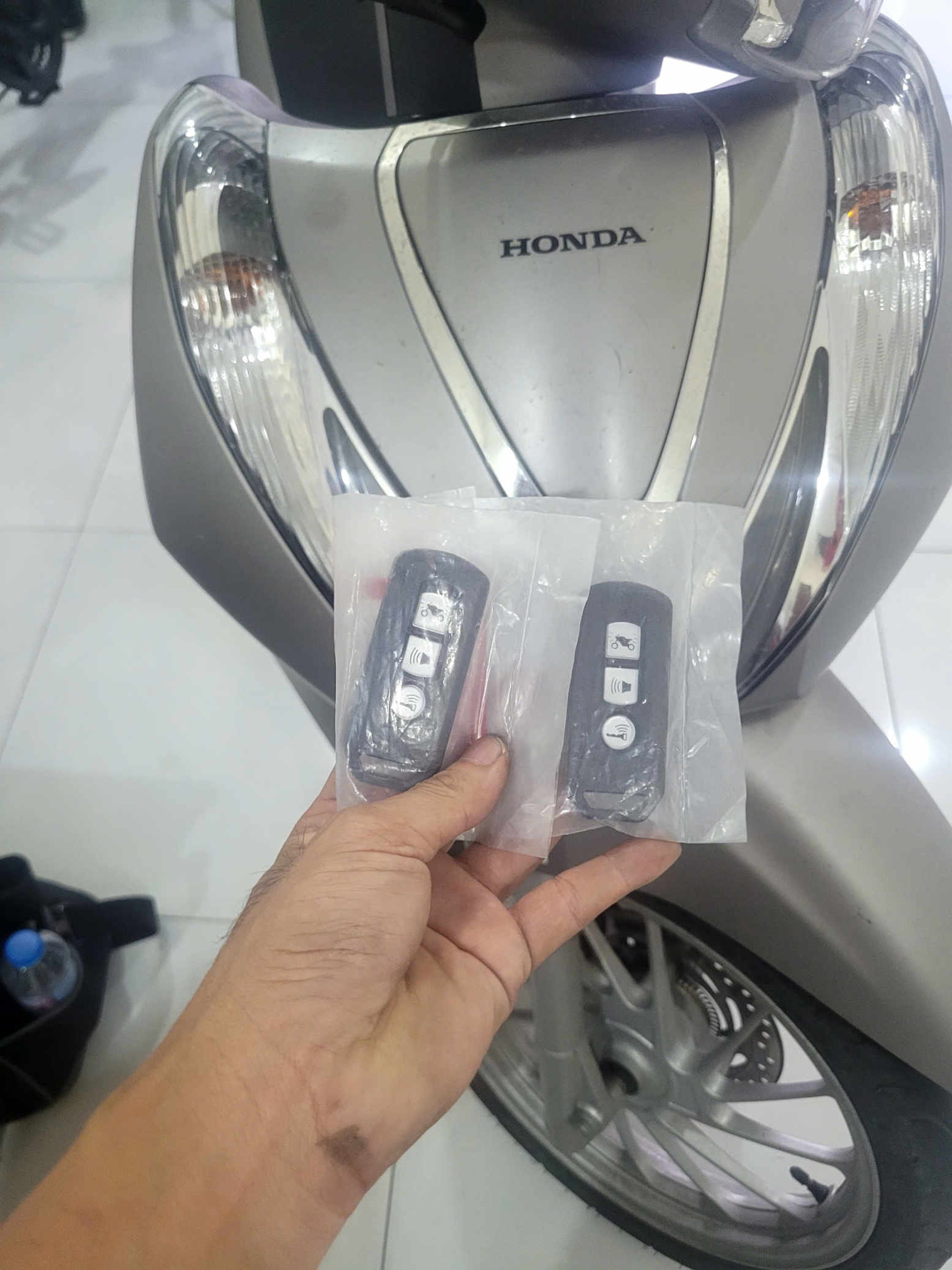 Chìa khóa remote thông minh cho xe máy Honda được cầm trước phần đầu xe màu bạc