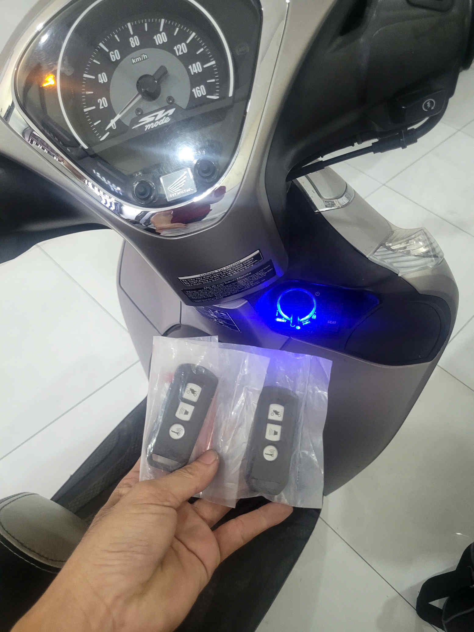 Chìa khóa thông minh Honda SH Mode mới trên tay trước bảng đồng hồ xe máy Honda