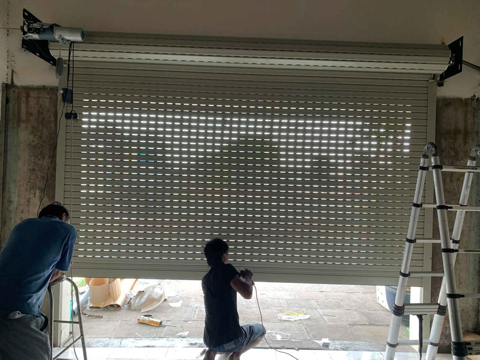 Lắp đặt cửa cuốn khe thoáng tự động cho mặt tiền nhà, thợ đang hoàn thiện thi công