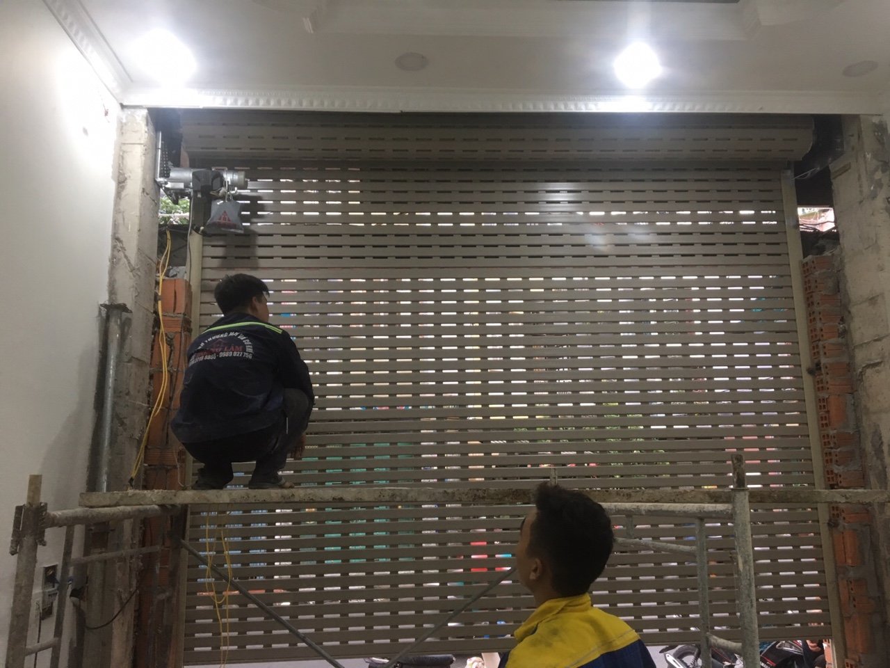 Thợ kỹ thuật lắp đặt cửa cuốn khe thoáng tự động cho mặt tiền nhà