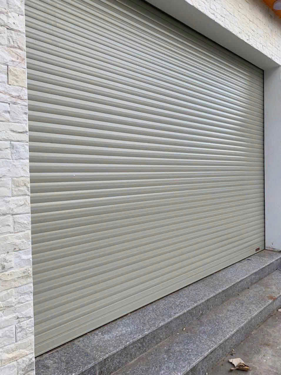 Cửa cuốn tôn màu xám lắp đặt cho mặt tiền nhà phố trên nền bậc tam cấp đá granite