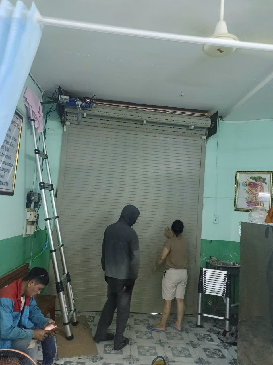 Thợ FIX365 đang kiểm tra và sửa cửa cuốn bị kẹt tại nhà khách hàng ở Quận 12, xử lý nhanh, an toàn, đúng kỹ thuậ