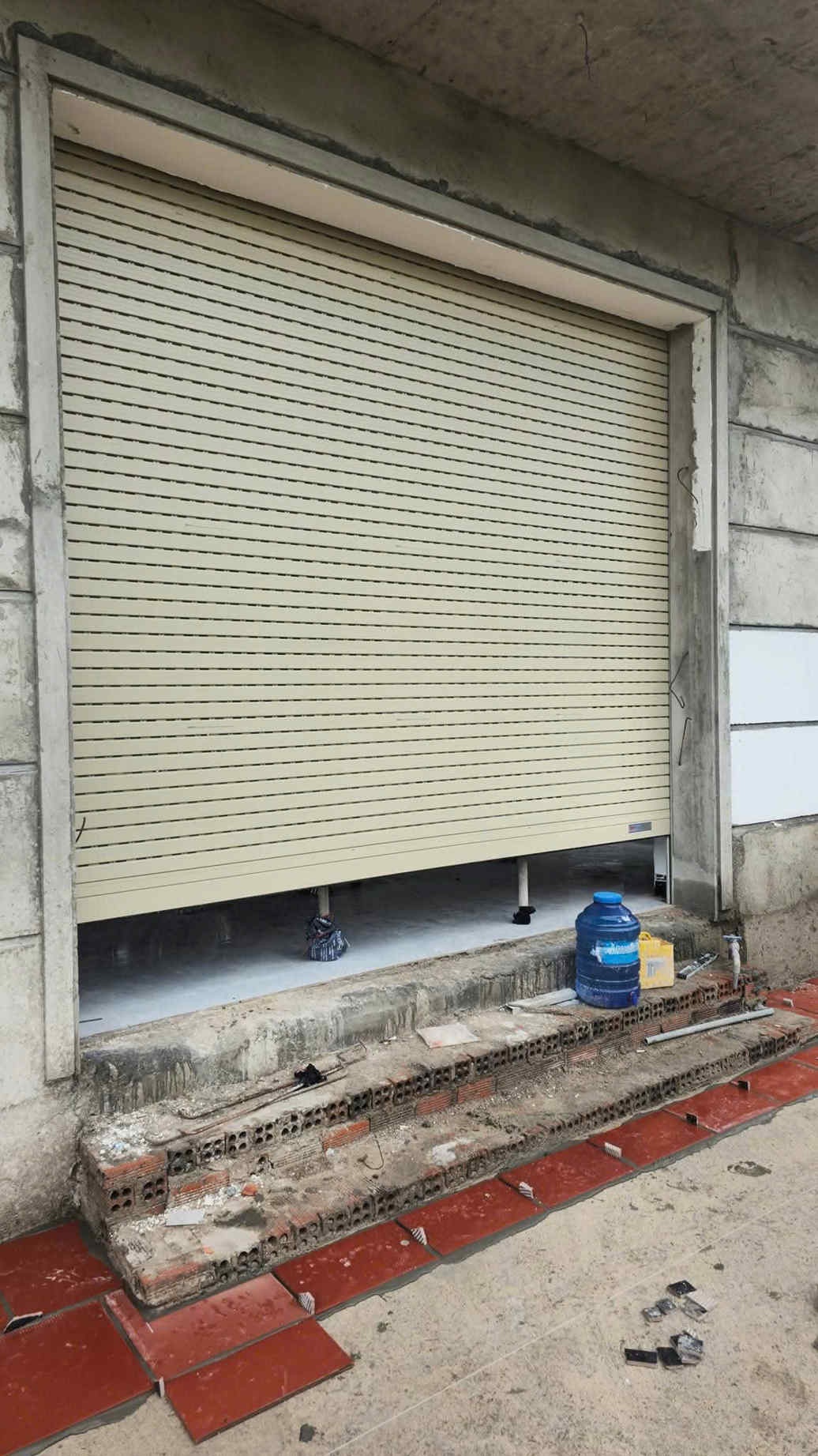 Cửa cuốn tôn màu kem lắp đặt cho mặt tiền nhà đang xây dựng