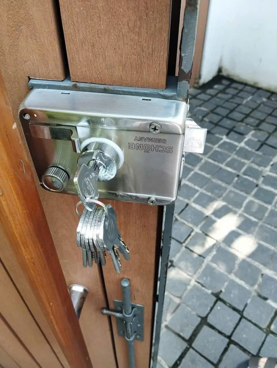 Ổ khóa cửa SCHONE Germany bằng inox gắn trên cửa gỗ kèm chùm chìa khóa treo ở ổ khóa